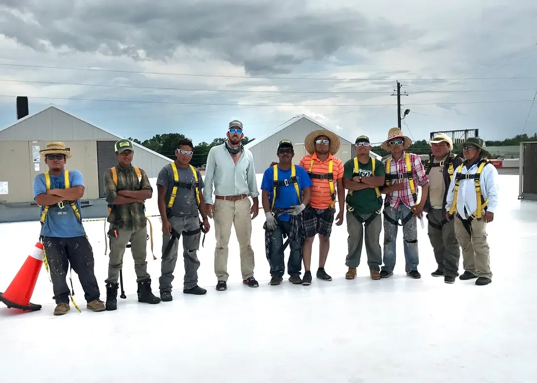 The Guyette roofing crew standing on top of a TPO recover job on a commercial roof in Montgomery, AL