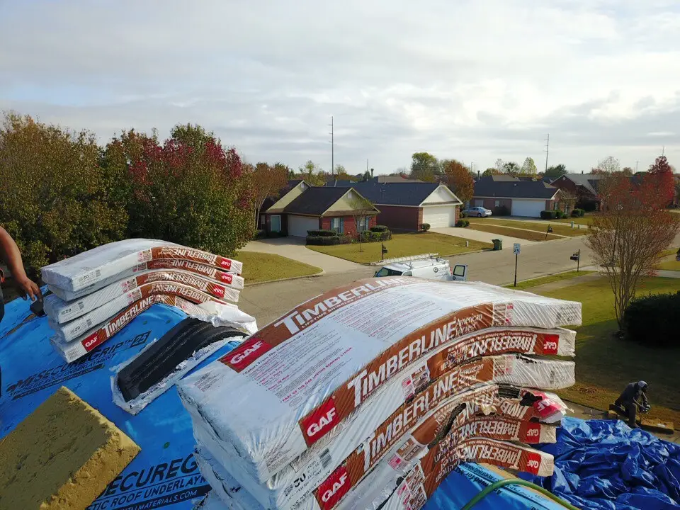 layers of shingles sitting on a roof ridge in preparation for a new roof installation